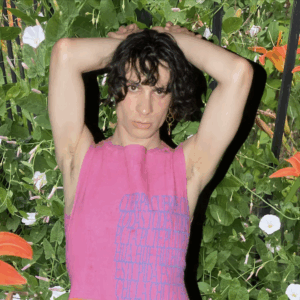 Noa Micaela Fields in a pink top by Mariposa Divina, in front of a lush verdant background.
